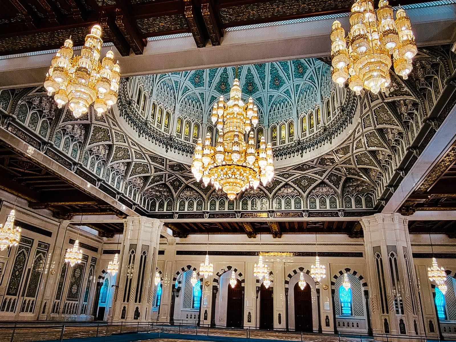 De gebedshal van de Sultan Qaboos-moskee, met koepel en kroonluchters