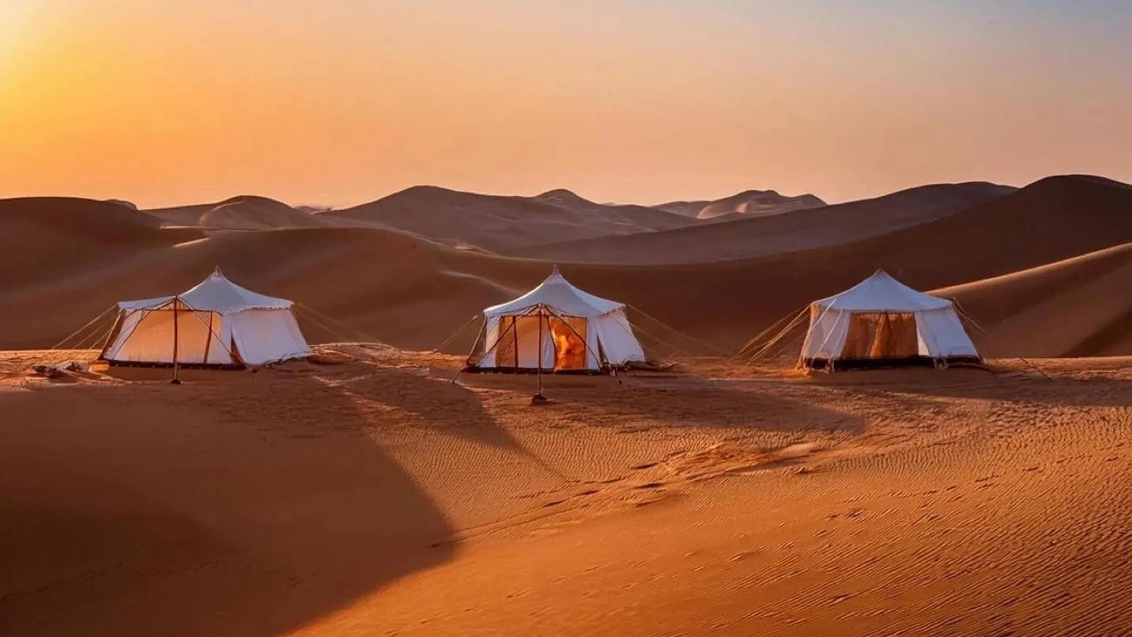 Sfeervol verlicht woestijnkamp tussen de duinen van de Wahiba Sands
